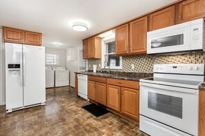 A kitchen with wooden cabinets, a white refrigerator, a microwave, a stove, and a dishwasher.