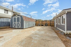 Un patio trasero residencial con un pavimento de concreto, un cobertizo y una valla de madera.