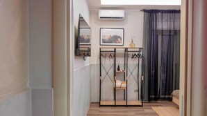 Une chambre moderne avec un plancher en bois, une armoire en métal noir, un tableau encadré au mur et une fenêtre ornée de rideaux légers.