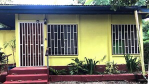 A yellow building with two barred windows and a red door. - Ojochal, Costa Rica
artist owned property, extensive gardens and pool (Ojochal)