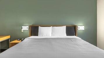 A hotel room with a large bed, two bedside tables, a wooden headboard, and wall-mounted lights.