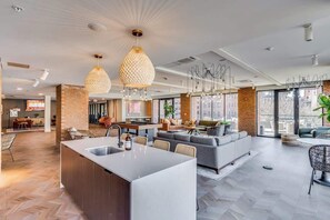 A modern kitchen with a central island, a dining area with a round table, and a living space with a sofa and chairs. - Downtown Walkable 1 Bed Apt (Cincinnati)