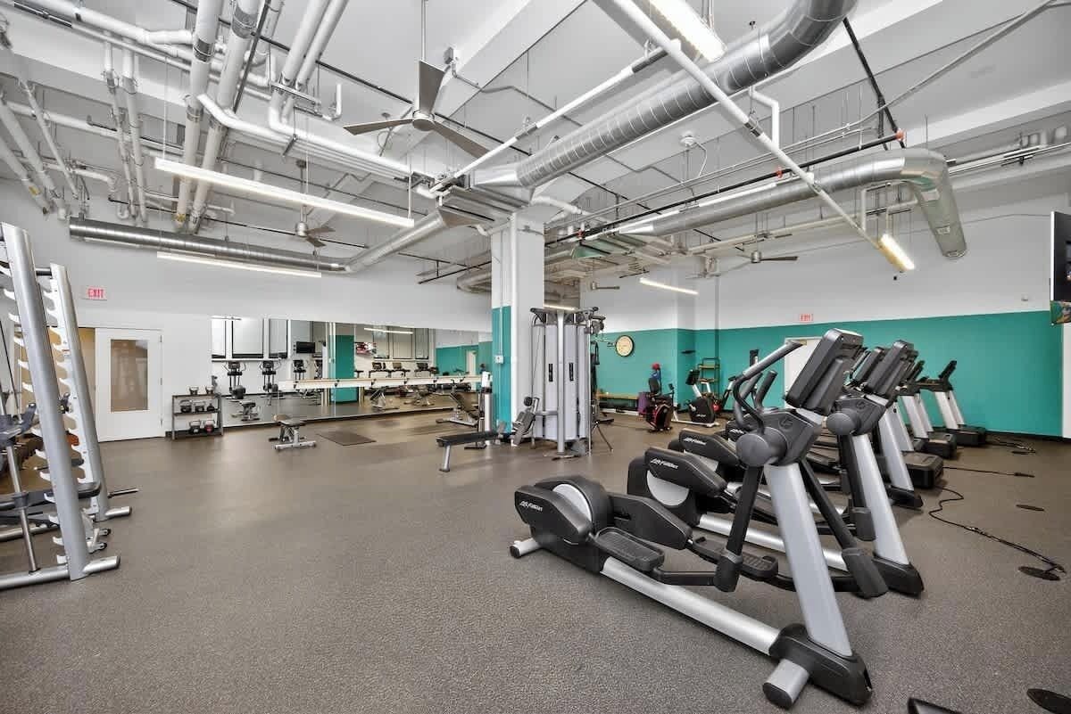 Une salle de sport équipée de tapis de course, d’appareils de musculation et de miroirs.