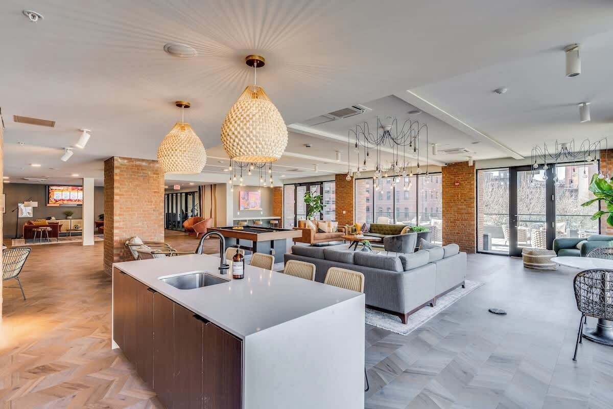 Una cocina moderna con una isla central, un comedor con una mesa redonda y un espacio de sala con sofá y sillones.