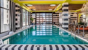 Ein Swimmingpool mit einer 9 Meter tiefen Markierung, umgeben von einem modernen Innenraum mit großen Fenstern und einer Holzbalkendecke.