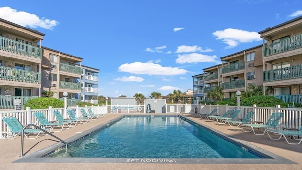 A swimming pool with a 3ft no diving sign, surrounded by lounge chairs and a white fence. - A Place at the Beach III 9520-2b (Myrtle Beach)