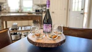 A bottle of Kirkland wine on a wooden coaster with four glasses on a table in a kitchen. - 15524 Candle Creek (Monument)