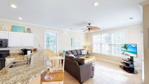A modern kitchen with granite countertops, white cabinets, and a dining area with a gray sofa and wooden chairs. - Caribbean Cove 504 (Myrtle Beach)