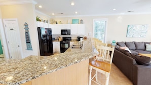 A modern kitchen with granite countertops, white cabinetry, and a central island. - Caribbean Cove 504 (Myrtle Beach)