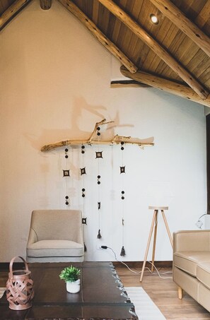 A cozy living room with a wooden ceiling, a hanging decorative piece, a sofa, a coffee table with a plant, and a small lamp. - 3 bedroom cottage in the best place of the Sacred Valley (Cuzco)