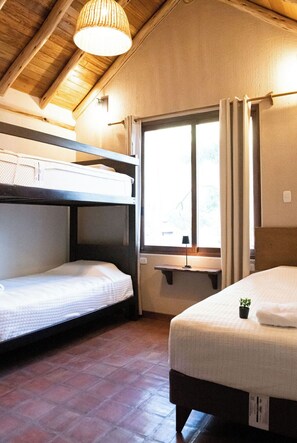 Une chambre avec des lits superposés, une fenêtre avec des rideaux, une étagère et une petite plante.