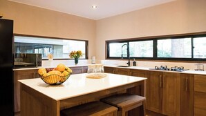 A modern kitchen with a central island, wooden cabinets, a microwave, and a large window providing natural light.