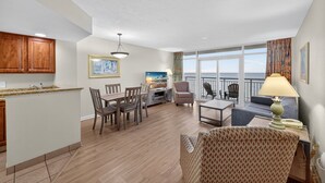Un vaste espace de vie comprenant une table à manger, des chaises, un canapé et un balcon offrant une vue sur l’océan.