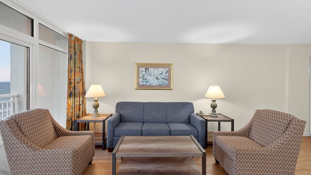 Une pièce comprenant un canapé, deux fauteuils, une table basse et un tableau au mur.