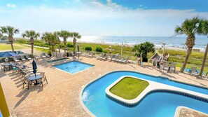 A pool area with two pools, lounge chairs, and a view of the beach. - Atlantica 655 (Myrtle Beach)
