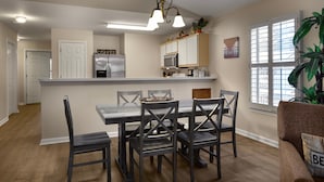 Una cucina moderna con isola centrale, sedie scure e lampadario a sospensione.