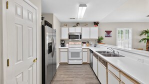 Una cucina moderna con mobili bianchi, elettrodomestici in acciaio inossidabile e pavimento in legno.
