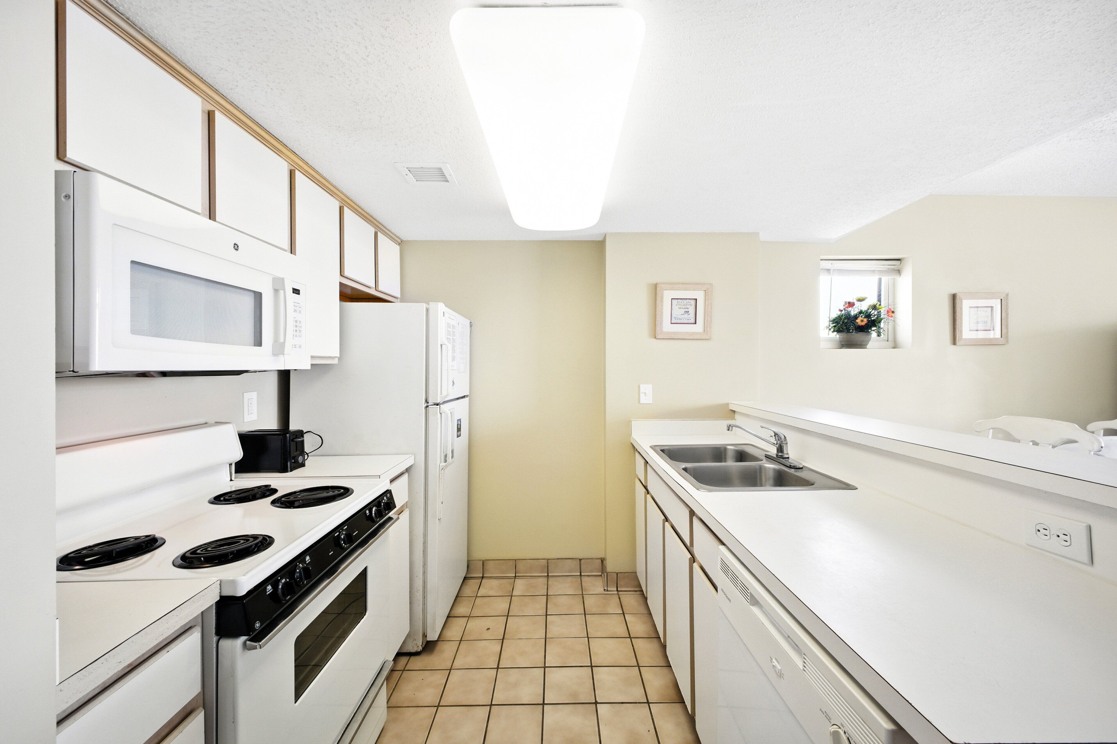 Una cucina moderna con elettrodomestici bianchi, pavimento piastrellato e colori neutri.