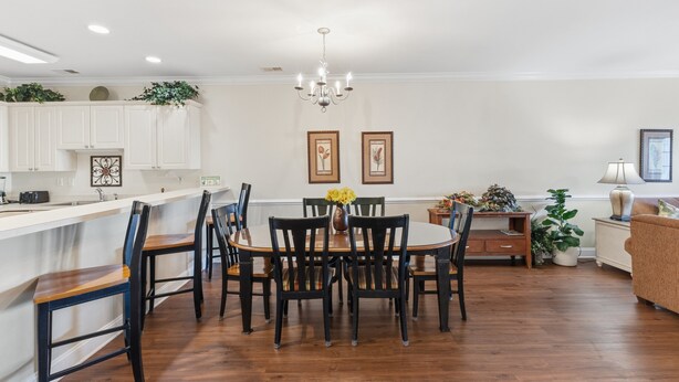 A spacious dining area with a round table surrounded by chairs, a chandelier, and framed artwork on the walls. - Magnolia Pointe Magnolia Lake 4812-302 (Myrtle Beach)