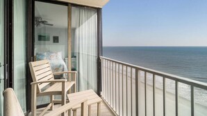 Een balkon met uitzicht op zee, een houten stoel en een tafel.
