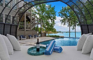 A poolside lounge with a view of the water, a bottle of wine, and a towel. - Lake Norman Getaway (Mooresville)