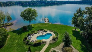 Une grande piscine privée, entourée d’une pelouse bien entretenue et d’une jetée qui s’avance sur un lac.