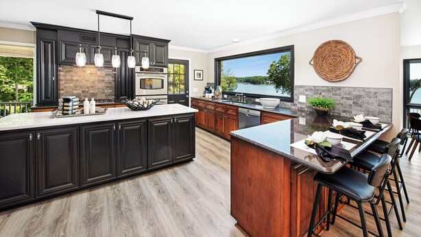 Une cuisine moderne avec des meubles de couleur sombre, un grand îlot central et une vue sur un lac.