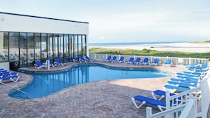 A pool area with blue lounge chairs and a view of the beach. - Sands Beach Club 1027 (Myrtle Beach)