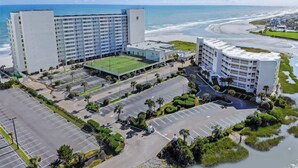 A hotel with a large parking lot, a tennis court, and a view of the beach. - Sands Beach Club 1027 (Myrtle Beach)