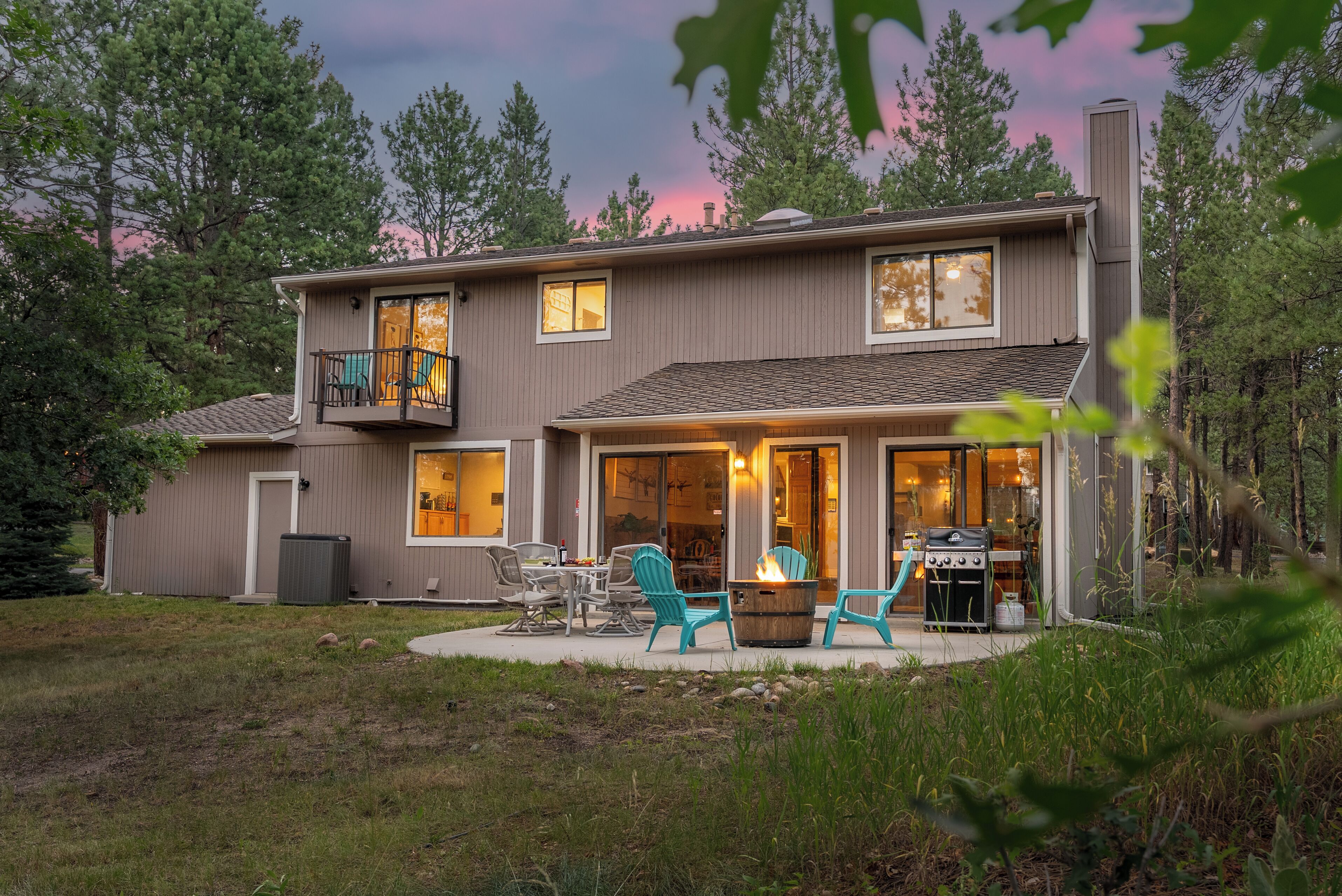 A two-story house with a patio area featuring outdoor furniture and a fire pit.