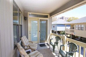 A balcony with chairs, a sliding glass door, and a view of neighboring buildings. - Guest Cottage 57 (Myrtle Beach)