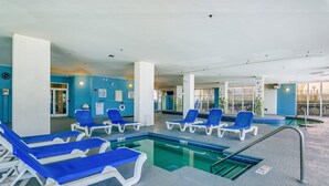 A pool area with blue lounge chairs and a pool. - Ocean Blue 303 (Myrtle Beach)