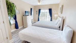 A hotel room with two beds, a desk, a TV, and a balcony with curtains. - Myrtle Beach Villas 205 A (Myrtle Beach)