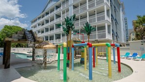 A multi-story hotel with a pool area featuring a water play structure and lounge chairs. - Myrtle Beach Villas 205 A (Myrtle Beach)