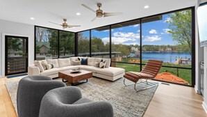 A modern living room with a large sectional sofa, a coffee table, and a view of a lake. - Blue Haven (Mooresville)