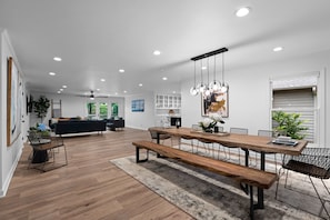 A modern dining area with a wooden table, benches, and pendant lighting. - Queens Cove (Mooresville)
