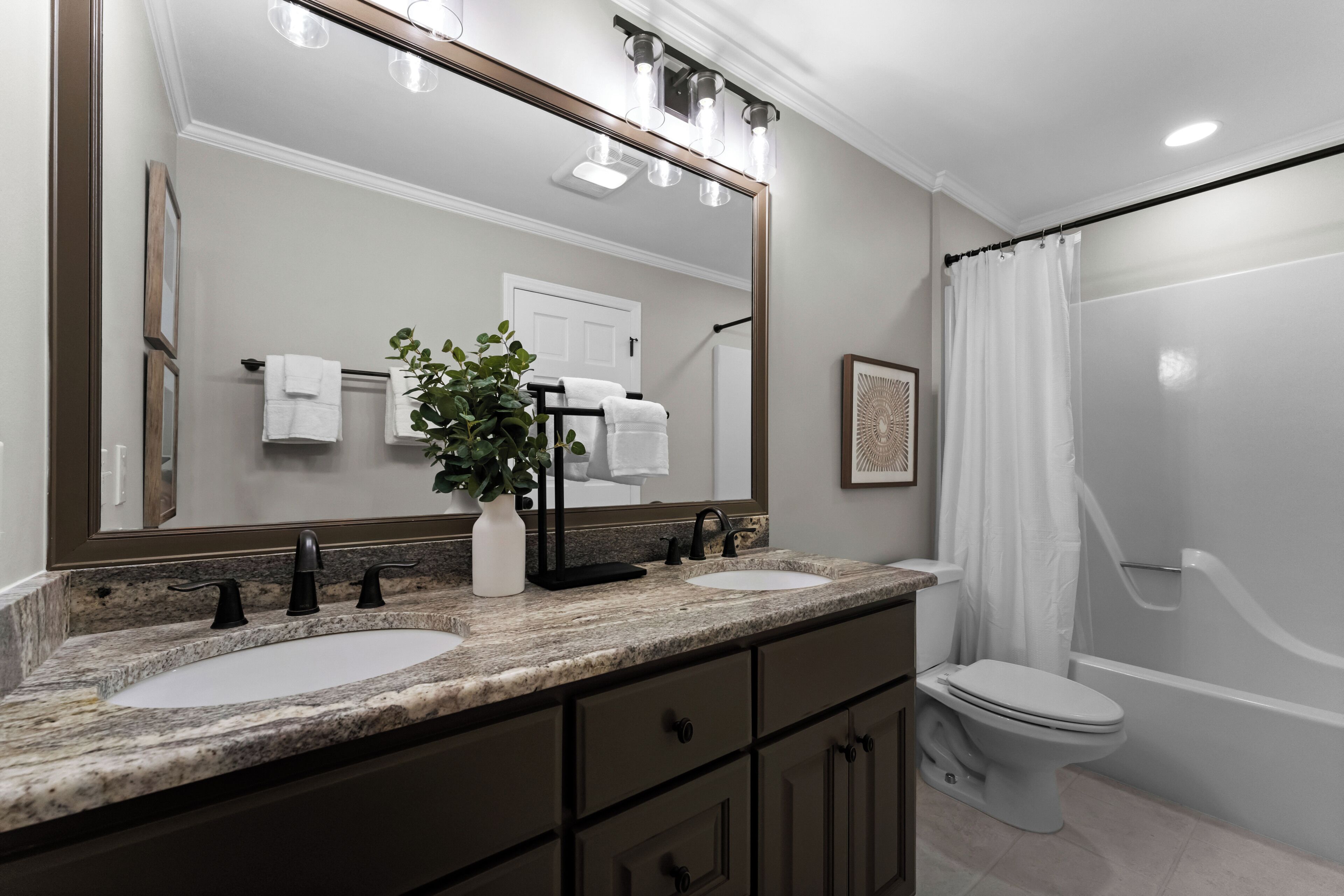 A bathroom with two sinks, a large mirror, and a shower curtain.