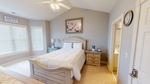 A bedroom with a bed, nightstands, a ceiling fan, a wall clock, and a door with a handle. - Magnolia Pointe Luster Leaf 4895-402 (Myrtle Beach)