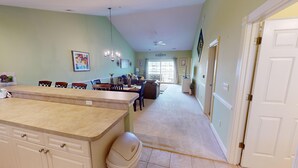 A spacious kitchen with a large island, dining area with chairs, and a hallway leading to a door. - Magnolia Pointe Luster Leaf 4895-402 (Myrtle Beach)
