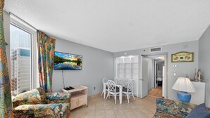 A living room with a TV, a dining table with chairs, a sofa, and a lamp. - Atlantica 903 (Myrtle Beach)