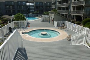 A rooftop pool area with a circular hot tub, surrounded by white railings and lounge chairs. - Shipwatch Pointe II M201 (Myrtle Beach)