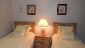 Camera doppia con due letti, ciascuno con una testiera in legno e un comodino con una lampada. Due quadri appesi alle pareti sopra i letti.