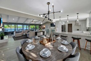 A modern kitchen with a central island, dining area with round table, and a view of a lake. - Southern Sunrise (Mooresville)