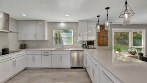 A modern kitchen with white cabinetry, a stainless steel dishwasher, and pendant lighting. - Southern Sunrise (Mooresville)