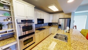 Eine moderne Küche mit weißen Schränken, Edelstahlgeräten, Granit Arbeitsplatten und einem eingebauten Backofen.