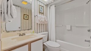 A bathroom with a sink, toilet, and bathtub. There are towels hanging on the wall and a framed picture above the mirror. - Atlantica 652 (Myrtle Beach)