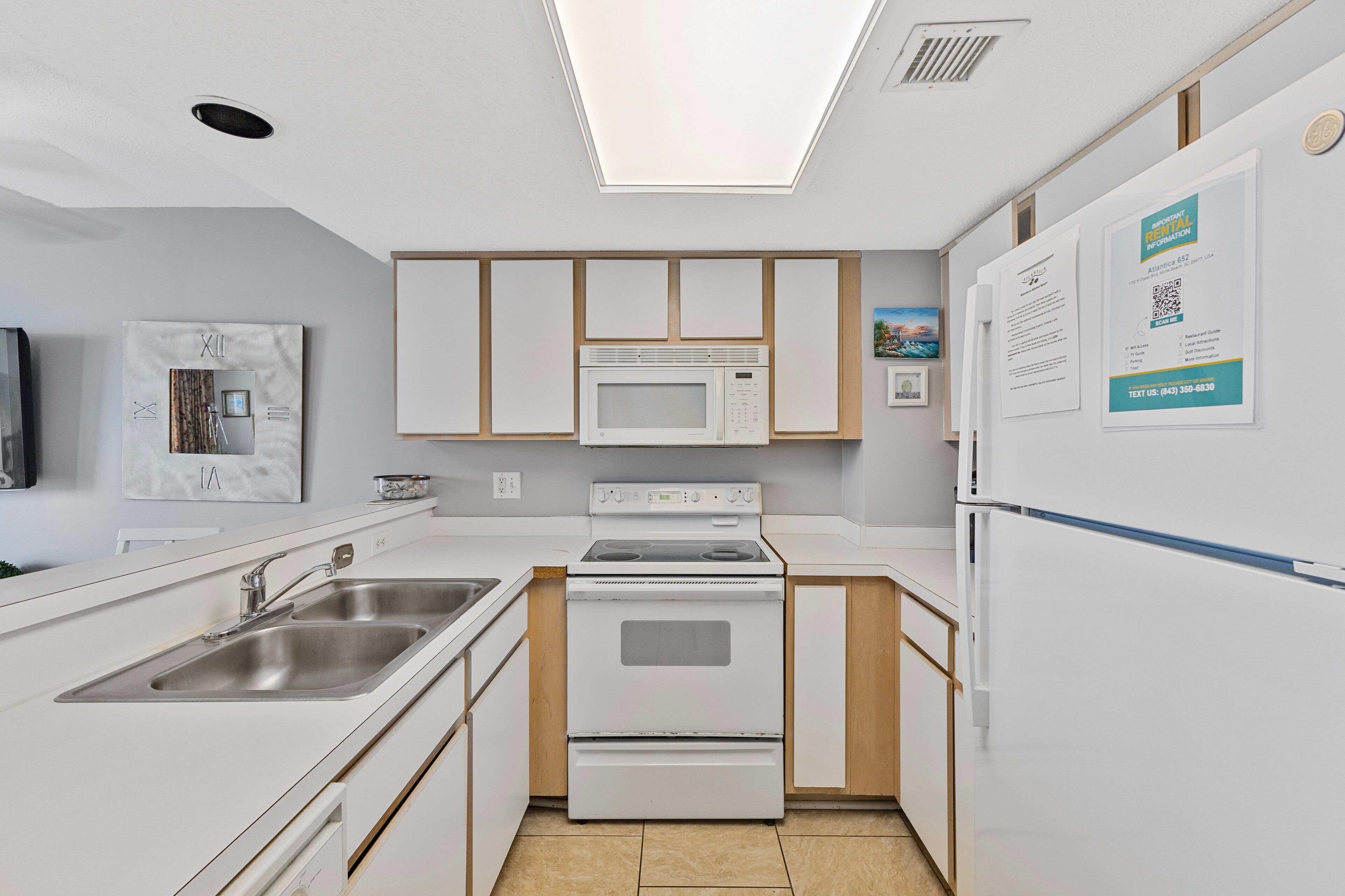 A modern kitchen with white cabinetry, a built-in microwave, a stove, and a refrigerator. There is a sink with a faucet, and a countertop with a dish rack.