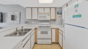 A modern kitchen with white cabinetry, a built-in microwave, a stove, and a refrigerator. - Atlantica 652 (Myrtle Beach)