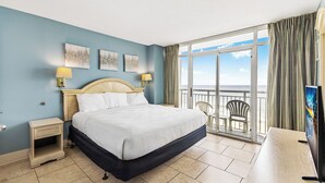 A hotel room with a bed, two bedside tables with lamps, a TV, and a balcony with a view of the sea. - Atlantica 652 (Myrtle Beach)