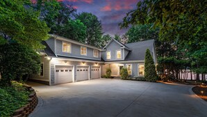 Ein zweistöckiges Haus mit überdachter Garage, umgeben von Bäumen und einem gepflegten Rasen.